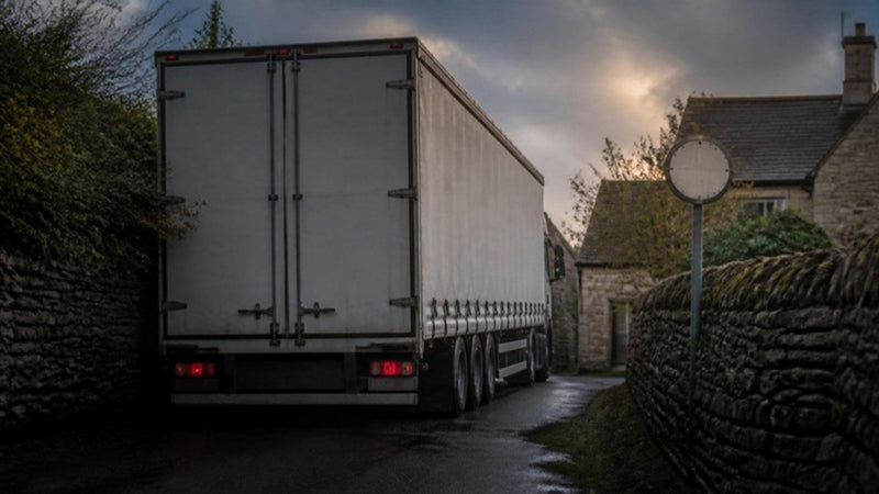 Articulated lorry wedged in a narrow stone-walled village lane after following a car sat nav